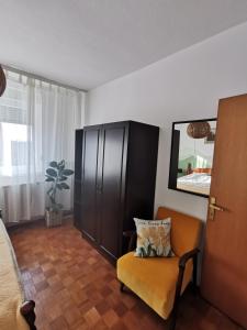 a living room with a chair and a cabinet at Apartman Aurora in Slavonski Brod