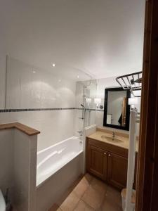 a bathroom with a tub and a sink and a mirror at Appartement 202 Geroli Lac d'Annecy in Duingt