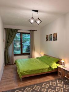 a bedroom with a green bed and a window at Alberta Apartments in Braşov