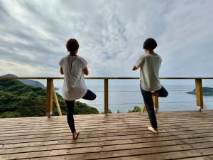 two people doing yoga on a deck overlooking the ocean at IZU Elysian View in Koura