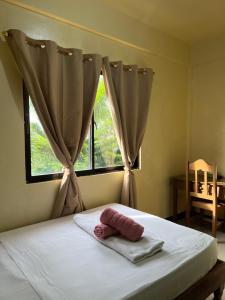 una cama con una toalla delante de una ventana en C View Resort, en Sipalay