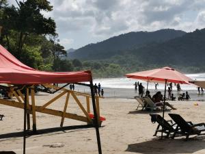 a beach with chairs and umbrellas and people on the beach at Karibik Ocean view Guesthouse Trinidad in Las Cuevas