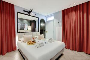 a bedroom with a large white bed with red curtains at Magnifique Studio 2P avec Jacuzzi et Cinema in Paris +5 photos