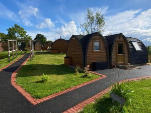 a group of tiny homes in a yard at Hedgehog Glamping Pod School House Farm in Leighton