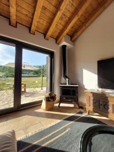 a living room with a fireplace and a large window at Casa rural La Casaca en plena sierra de Gredos in Los Narros