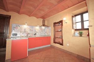 a large kitchen with red cabinets in a room at Casa de la Jara by SIERRA VIVA in La Nava