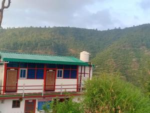 a house with a green roof on a mountain at Odyssey Stays Khirsu in Pauri