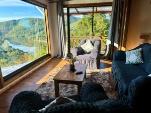a living room with couches and a table and a large window at Casa con vista al rio Cutipay in Niebla