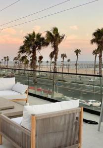 een balkon met palmbomen en uitzicht op het strand bij Beach House with Rooftop Jacuzzi in Huntington Beach