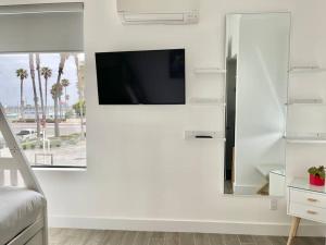 a living room with a tv on a white wall at Beach House with Rooftop Jacuzzi in Huntington Beach