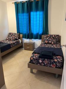 two beds in a room with blue curtains at Bayview Bliss Appartement just 50 steps from the beach in Santa Maria
