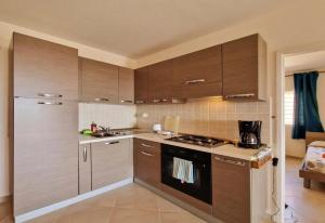 a kitchen with brown cabinets and a stove top oven at Bayview Bliss Appartement just 50 steps from the beach in Santa Maria