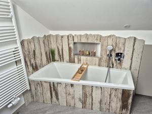 een bad in een kamer met een houten muur bij Ferienwohnung Mariposa in Böbing +9 foto's
