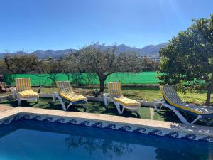 eine Gruppe von drei Stühlen und einem Pool in der Unterkunft Finca el Pereo in Alhaurín el Grande