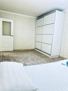 a bedroom with a white bed and a door at микрорайон 9 in Almaty