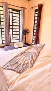 a white bed in a room with two windows at Jazzawanda Forest Retreat in Nairobi