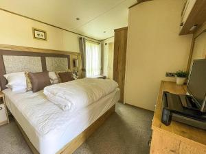 a bedroom with a large white bed and a television at Modern Caravan With Large Decking Area, Ref 60057Ch in Saxmundham +10 photos