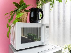 a microwave sitting on top of a table with plants at Shinjuku, 3min walk from Nishi-Shinjuku 5-chome Sta, 3min Shinjuku Sta Switch, Wi-Fi ,Pocketwi-Fi in Tokyo