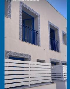 a white building with blue windows and a fence at Panhouse Rooms & Suite in Palermo