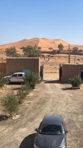 a car parked on a dirt road in the desert at Tifinagh Guest House in Merzouga