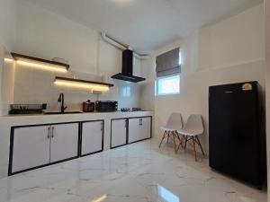 a kitchen with white cabinets and a black refrigerator at The Oasis Inn in Hua Hin