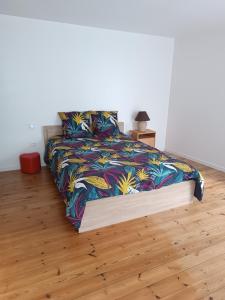 una camera da letto con un letto con un piumone colorato di Au coin de la rue a Saint-Vincent-Sterlanges