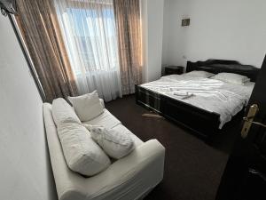 a bedroom with a bed and a couch next to a window at Plaiul Bucovinei in Horodnic de Sus