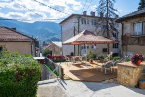 a patio with an umbrella and chairs on a wooden deck at Spacious and Bright 2BDR Apartment in the Old Town in Sarajevo