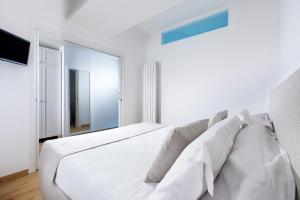 a white bedroom with a large white bed with pillows at Solymar Suite in Sorrento