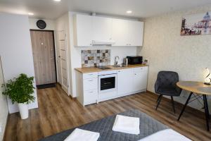 eine Küche mit weißen Schränken und einem Tisch und Stühlen in der Unterkunft Baltic Serenity - SELF CHECK-IN in Klaipėda + 4 Fotos