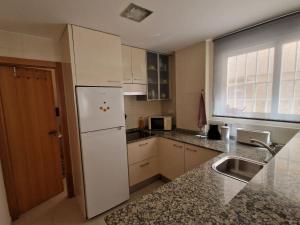 a kitchen with a white refrigerator and a sink at Lovely Beach flat, ground floor, with fast WiFi, AC and Heating in Bellreguart +6 photos
