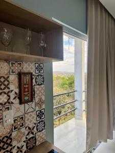 a kitchen with a window and a tiled wall at Flat Jade - Alto Paraíso - Chapada dos Veadeiros in Alto Paraíso de Goiás
