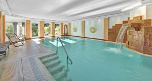 a large swimming pool with a waterfall in a room at DIANA Naturpark Hotel - Partnerbetrieb von "Oberstaufen PLUS GOLF" in Oberstaufen