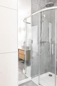 a shower with a glass door in a bathroom at Old Town Vibes Premium AON Apartment in Gdańsk +53 photos