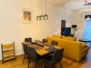 a living room with a yellow couch and a table and chairs at Schönbrunn Garden Apartments in Vienna