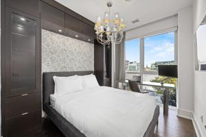 a bedroom with a large bed and a chandelier at PARC LOFT Penthouse with 4bd-WFH-PS5-CN Tower Views in Toronto