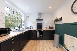 a kitchen with black cabinets and a large window at Luke Stays- Newton Hall Cottage in Durham