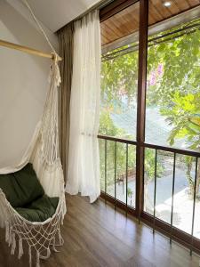 a hanging hammock in a room with a large window at Forest Tag Homestay in Hue