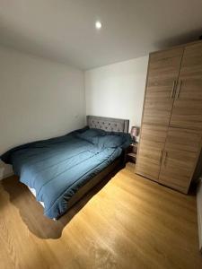 1 dormitorio con 1 cama azul y suelo de madera en Appartement 1 chambre vu sur jardin, en La Roche-sur-Yon