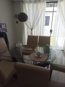 a dining room with a glass table and chairs at Quarto 1 para mulher in Maringá