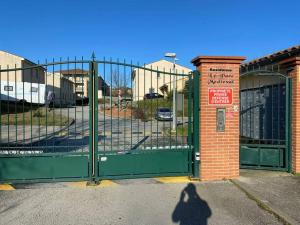 a person standing in front of a green gate at Le Voyage Bleu, Clim Parking in Carcassonne