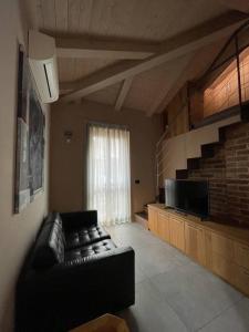 salon ze skórzaną kanapą i telewizorem w obiekcie Loft Cùntra Maestra w Asti