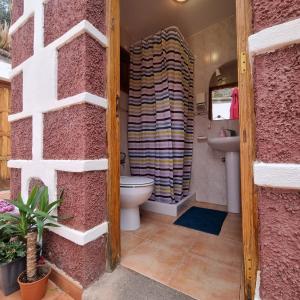 a bathroom with a toilet and a pink wall at Villa Margarita in Santa Lucía