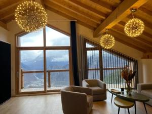 a living room with chairs and a table and large windows at Chalet La Tarine in Saint-Marcel