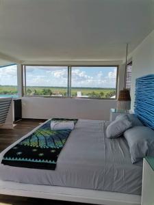 a large bed in a room with large windows at Bonita habitación con pequeña piscina a aire libre in Puerto Morelos