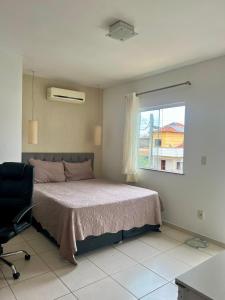 a bedroom with a bed and a window and a chair at Casa com piscina, churrasqueira e ar condicionado em condomínio in Cabo Frio +58 photos