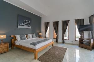 a bedroom with a bed and a tv and windows at Villa Skyler Seminyak in Seminyak