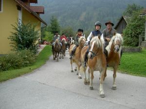 un grupo de personas montando caballos por una calle en Gasthof Neuwirt, en Schöder