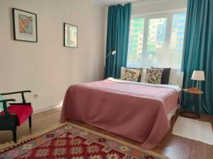 a bedroom with a pink bed and a window at ЖК Шугыла Apartment in Shugyla