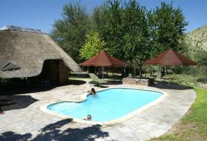 una mujer está en una piscina en un patio en Etusis Lodge en Usakos